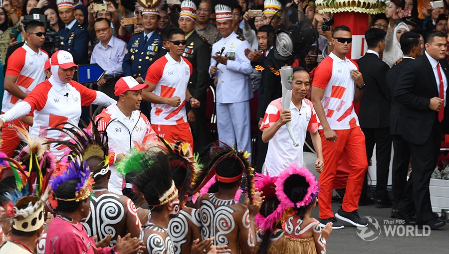 Indonesia's President Joko Widodo carries a torch of the 2018 Asian Games as he runs with Sport and Youth Minister Imam Nahrawi (L) during the torch relay at the presidential palace in Jakarta on August 17, 2018. #AsianGames2018     